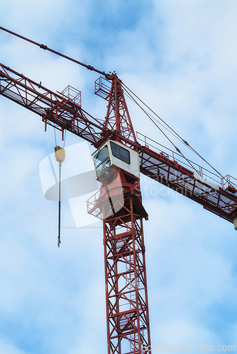 Image of Crane, construction and blue sky background for building with heavy metal, steel or machinery outdoor. Hoist in city, urban or industrial development in a low angle of overhead equipment and tools