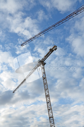 Image of Crane, construction and clouds or blue sky background for building with heavy machinery or material outdoor. Hoist in city, urban or industrial development with low angle, tools or overhead equipment