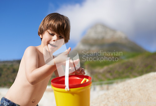 Image of Happy, beach and child with bucket and toys on summer holiday, vacation and relax by ocean. Childhood, building sand castle and young boy playing for adventure, fun and weekend by seaside in nature