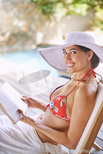 Image of Woman, bikini and smile for portrait, book and hat at resort in Dubai by swimming pool. Female person, holiday and happy in summer, beauty and outdoor for wellness and relaxation in travel trip