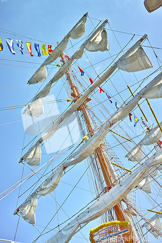 Image of Sailing, ship and mast outdoor with flag for travel, journey and low angle of blue sky in summer. Boat, wood pole and vintage schooner vessel on a cruise, rigging and transport in nature with rope