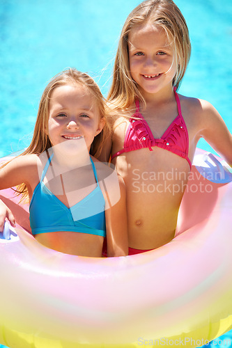 Image of Girls, summer and pool with inflatable tube on vacation, swimwear and fun in sunlight for holiday. Happy, kids ad entertainment with smile and toy, children in water for swimming together outdoors