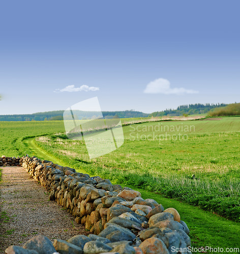 Image of Sky, field and stone wall in countryside for farming, agro growth or crops for development in nature. Background, travel and landscape of meadow horizon, lawn or natural pasture for grass and ecology