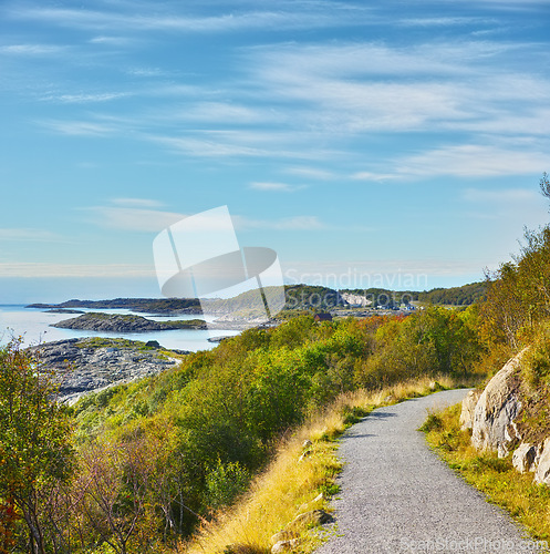 Image of Road, landscape and sky with ocean in nature for travel, adventure and trees with mountain view in Norway. Path, coastline and location with hill, roadway and environment for holiday and direction