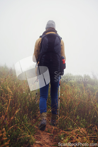 Image of Person, hiking and back in countryside for trekking, sticks and support for fog trail in mountain. Athlete, backpack and sport gear for safety in cold environment, slippery and walking for fitness