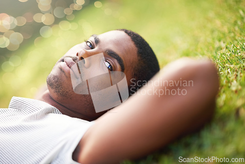 Image of Portrait, serious and black man on grass in garden of summer park for peace, wellness or mindfulness. Relax, nature and field with confident young person lying on ground for break, chill or rest