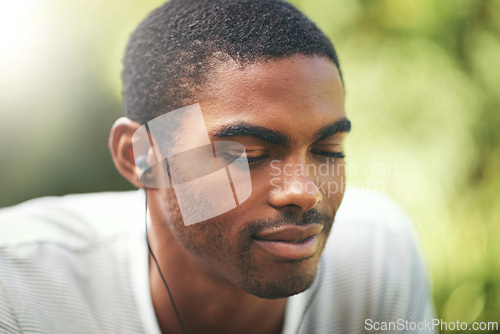 Image of Face, music and relax with black man in nature or park outdoor for summer, peace and quiet. Garden, radio and wellness with calm young person streaming audio or sound on earphones in backyard