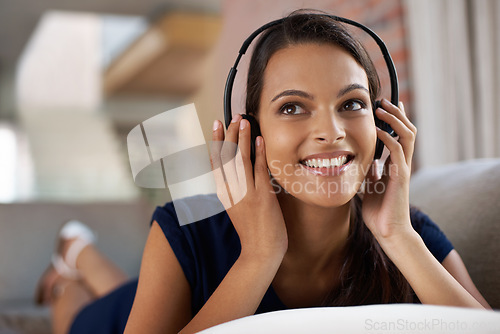 Image of Face, music and thinking with woman on sofa in living room of home for weekend free time or relax. Smile, streaming and idea with happy young person listening to radio on headphones in apartment