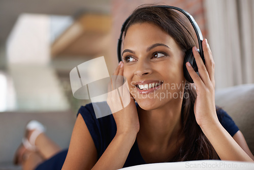 Image of Face, smile and music with woman on sofa in living room of home to relax on weekend time off. Sound, streaming and headphones with happy young person listening to radio in apartment for break