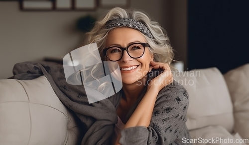 Image of In her sunlit living room, the modern elderly woman exudes sophistication, wearing glasses, creating a chic and cozy atmosphere.