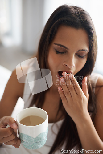 Image of Yawn, tired and woman with coffee in bedroom with caffeine to wake up in morning at home. Exhausted, burn out and sleepy young female person drinking cappuccino or latte for fatigue in apartment.