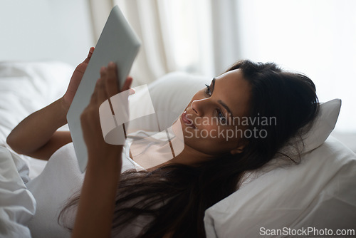 Image of Tablet, bed and social media with woman in morning to relax, wake up on weekend or reading ebook. Technology, app and internet with young person in bedroom of home for online literature or story