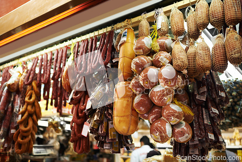 Image of Hooks, butcher and dry meat in shop for traditional food, groceries or products in Germany. Supermarket, deli and fermented or smoked sausages hanging in row for production in grocery store.