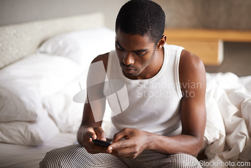 Image of Black man, typing and bed with phone for social media, networking or communication at home. African male person on mobile smartphone in morning for online chatting, texting or app in bedroom at house