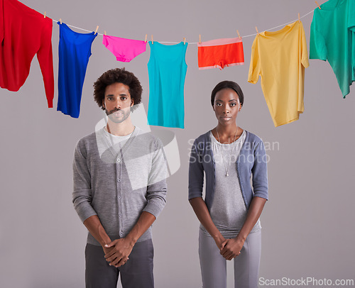 Image of Portrait, people and laundry in studio with clothes, hanging and drying on washing line. Black person, man and woman in marriage or dating, cleaning and routine while standing on gray background