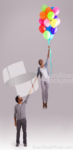 Image of Balloon, flying and couple in studio for growth, celebration and present on gray background. independant, opportunity and isolated man and woman holding hands with inflatable for party and surprise