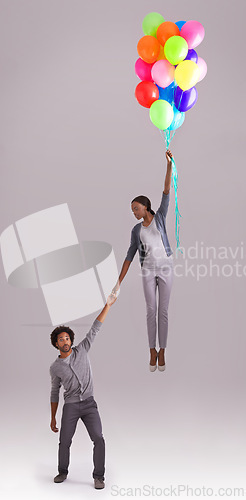 Image of Balloon, float and couple in studio for birthday, celebration and present on gray background. Trust, flying and isolated man and woman holding hands with inflatable for party, gift and surprise