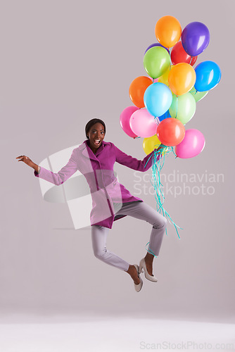 Image of Balloon, jump and portrait of happy black woman in studio for birthday, celebration and present. Fashion, excited and isolated person with inflatable for party, gift and surprise on gray background