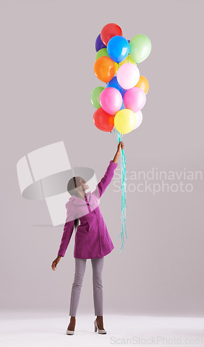 Image of Balloon, color and black woman in studio for birthday, celebration and present. Happy, excited and wow with isolated person smile with inflatable for party, gift and surprise on gray background