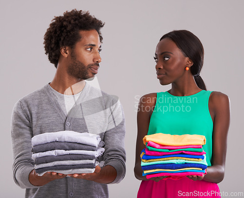 Image of Couple, folded clothes and laundry in studio for chores, domestic and housework together. Black people, man and woman in relationship or married are organizing, color code shirts on gray background