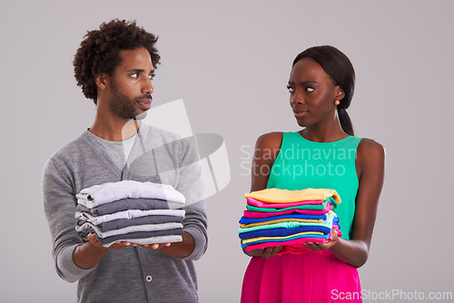 Image of People, studio and pile of laundry in hand for neat, cleaning day or washing clothes together. Couple, surprise and shocked for organised wardrobe with color choice, fashion or ocd on grey background