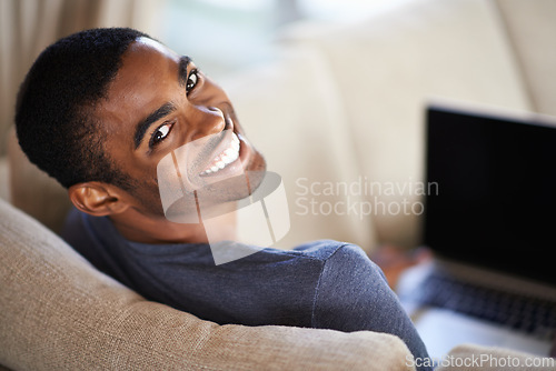 Image of Man, portrait and happy on sofa with relax for internet streaming, communication or online games in home. Student, african person and face with smile, laptop or technology in living room for research