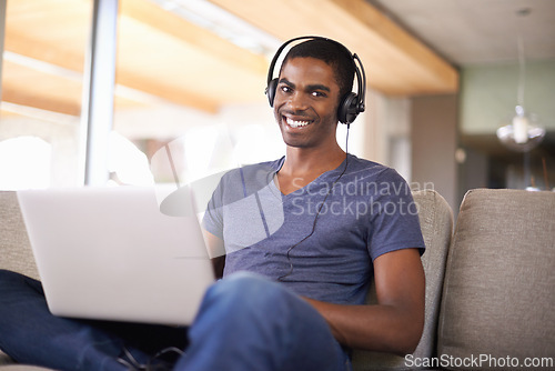 Image of Man, portrait and music with laptop on couch for internet streaming, podcast or online research with smile. Student, black person or technology with headphones for relax, studying or learning in home