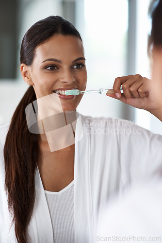 Image of Woman, brushing teeth and toothbrush for dental, mirror with smile in bathroom for morning routine. Oral hygiene, wellness and orthodontics with toothpaste for fresh breath, health and self care