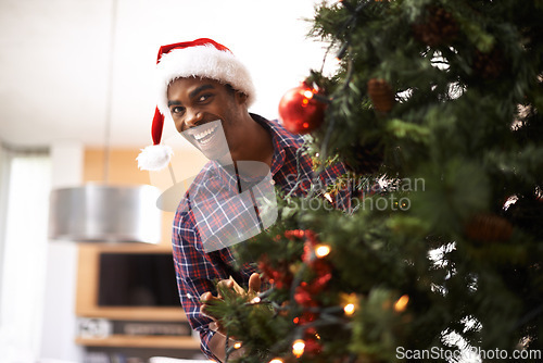 Image of Portrait, smile and black man with Christmas tree in living room of home for decoration or holiday. Celebration, December or festive and happy young person in apartment with Santa hat for tradition