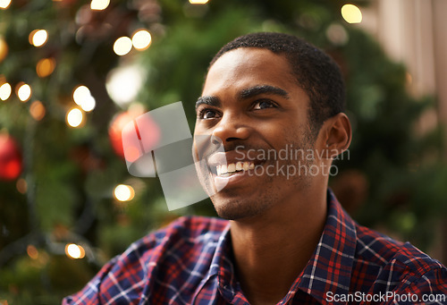 Image of Man, thinking and happy in home on christmas for celebration, holiday and festive spirit in living room. African person, thoughtful and smile on xmas with relax, confidence and vacation in apartment