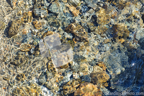 Image of Sunlight sparkling on clear rocky streambed in daylight