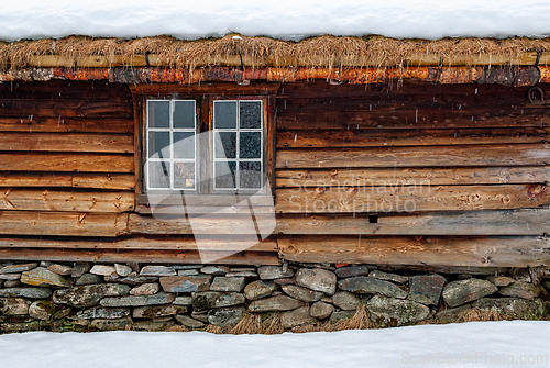 Image of Traditional wooden cabin with thatched roof in a snowy landscape