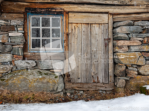 Image of Rustic wooden cabin with stone foundation in a snowy landscape a