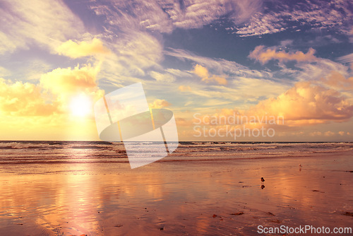 Image of Beach, sunset and clouds in blue sky with waves, water and sand in seaside or lake. Tourism, destination and vacation for summer ocean, landscape and environment for holiday or travel in California