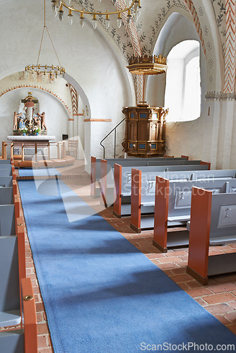 Image of Christian, shrine or altar in church for religion, worship and spiritual space for ceremony in Danish culture. Praise, god and sculpture of Jesus in chapel with furniture, seat on aisle and hallway