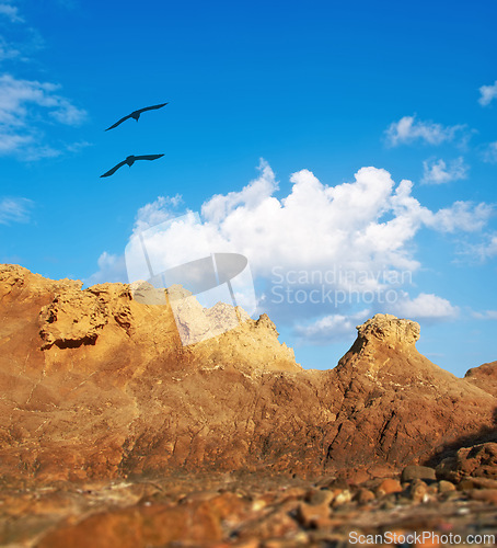 Image of Mountain, birds and natural landscape with blue sky, sun and calm clouds on peak at travel location. Nature, cliff and environment with earth, flight and holiday destination in wilderness with rocks