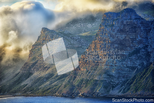 Image of Mountain, clouds and sunset at ocean cliff with natural landscape, hill and beach at travel location. Nature, cloudy sky and sustainable environment with earth, sea and island holiday destination