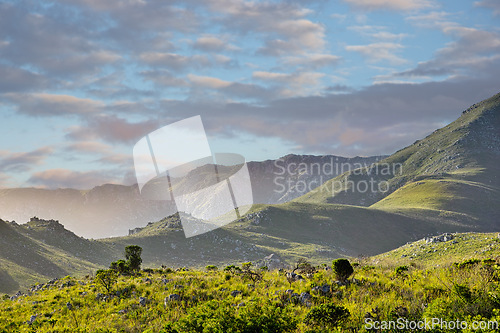 Image of Mountain, clouds and sunset landscape with field, blue sky and calm hill for travel location. Nature, fog and sustainable environment with earth, peace and holiday destination with conservation