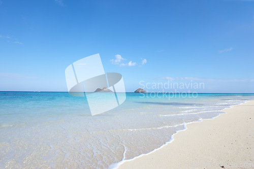 Image of Ocean, shore and blue sky for holiday, sand and rocks in Hawaii for peace and tranquility. Seaside, waves and summer for vacation, location and beach for clear water on travel and tropical trip