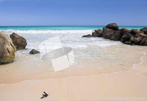 Image of Beach, blue sky and ocean, landscape with rocks in nature and environment, sand at shore with travel destination. Horizon, waves and seascape in natural background, tropical location or island