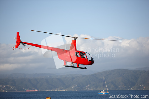 Image of Helicopter, sea and emergency transport or landscape for search and rescue, medical service or patrol in sky. Chopper, aerial view and ocean environment for help on mountain, coast guard or lifesaver