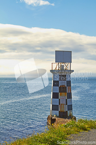 Image of Lighthouse, ocean and blue sky by beach in nature for holiday, vacation or travel destination. Water, clouds and signal tower by sea for outdoor summer weekend trip on tropical island in cape town.