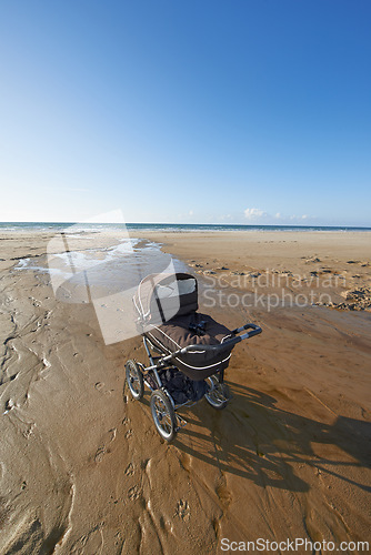 Image of Stroller, sand and blue sky by beach in nature for travel, vacation or holiday in summer. Baby pram, coast and ocean by seashore for tropical weekend trip on outdoor island destination in Cape town.