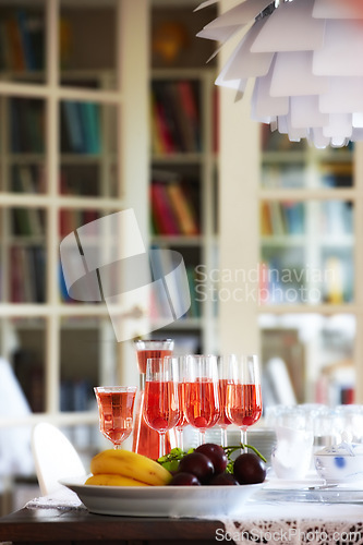 Image of Red, wine and fruit on dinner table, celebration glasses for holiday and party in home living room. Hospitality, guest preparation with alcohol beverage, bookshelf and vacation event or entertainment