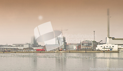Image of Harbor, industrial buildings and town in outdoors, treatment plant and development by factory. Production, warehouse and power station or refinery in Aarhaus, Denmark and river or lake outside