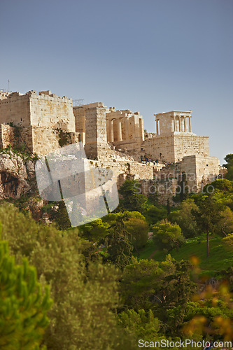 Image of Architecture, artistic building and history of parthenon in Athens Acropolis with trees, nature and grass in Greece. Traditional temple, design and walls in landscape blue sky, rocks and marble