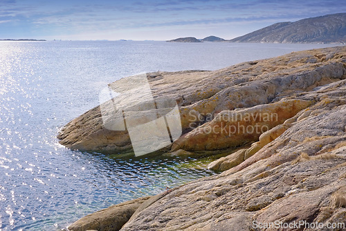 Image of Rocks, nature and ocean by beach with blue sky, waves and coastline for outdoor travel destination. Seascape, water and drone of sea by stones on tropical island for summer holiday, vacation or trip.