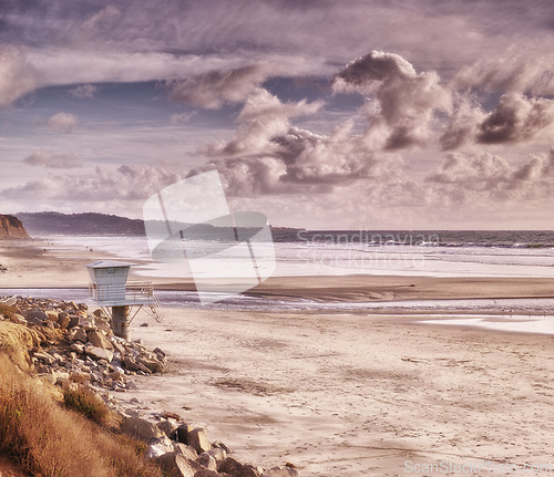 Image of Clouds, sky and ocean by beach with sand for travel, vacation or holiday in summer. Seascape, nature and tropical island with sea, rocks and guard chair for outdoor weekend trip in Cape town.