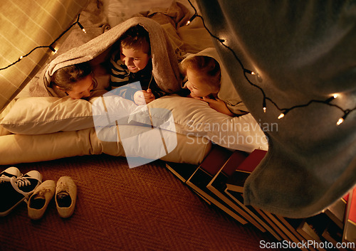 Image of Kids, happy and sleepover in tent at night with conversation, bonding and holiday adventure or vacation. Funny friends or children by fairy lights, pillows and blanket at home for fun storytelling