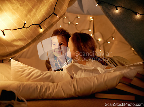 Image of Children, happy and playing in tent at night with love, kiss and bonding for holiday adventure or vacation. Young boy, girl or kids by fairy lights, pillows and blanket at home with thinking or ideas